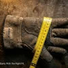 Industrial worker measuring hand circumference with a flexible tape measure to find the correct work glove size for safety and protection