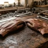 Close-up of brown goatskin leather work gloves on a workbench showing natural grain texture and premium leather quality